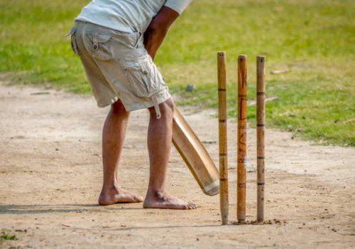 A young Indian boy playing cricket. View of a right handed batsman with all three stumps visible.